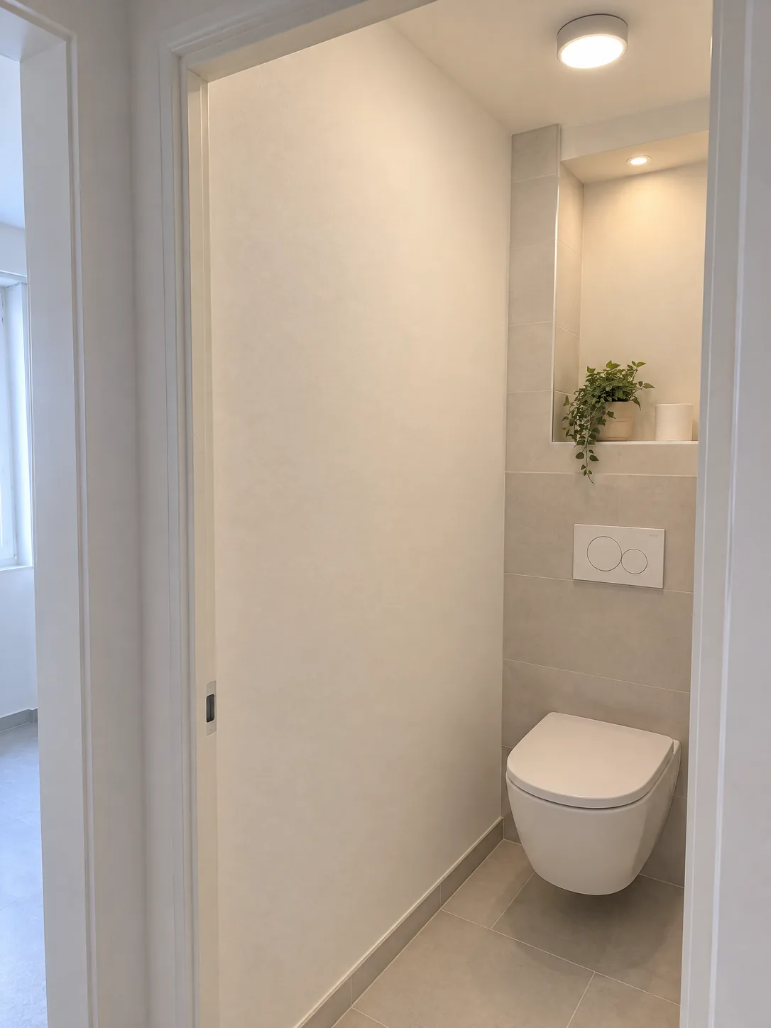 WC suspendu avec niche éclairée et carrelage clair